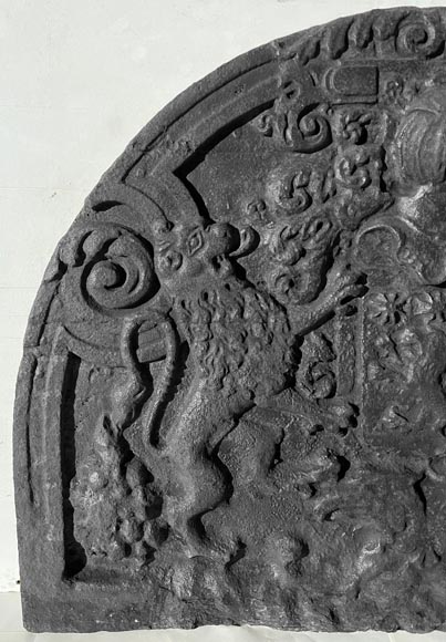 A semicircular cast iron fireplace plaque, decorated with a coat of arms, surmounted by a helmet and framed by lions. A semicircular cast iron fireplace plaque, decorated with a coat of arms, surmounted by a helmet and framed by lions.-1
